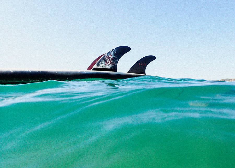 Deflow LEGI ALONSO thruster fins on a surfboard in the water.